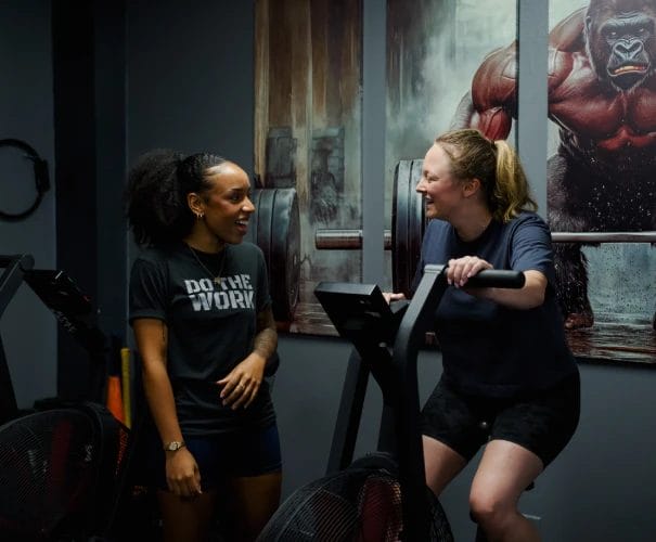 Woman riding gym bike with coach supervision
